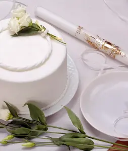 Eine weiße Torte neben einer gold-weißen Kerze am festlich gedeckten Kommunionstisch