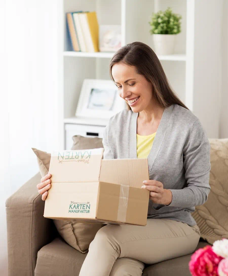 Tischkarten Kommunion Konfirmation werden geliefert, Frau packt Paket mit Karten aus