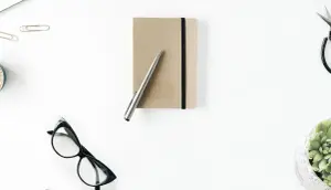 Schreibtisch mit goldenem Buch und Stift aus der Vogelperspektiven, hier werden hochwertige Klappkarten und Umschläge erstellt