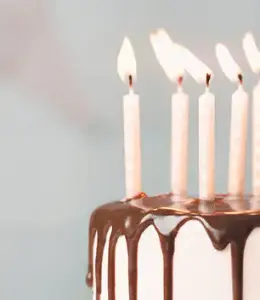 Creme farbene brennende Kerzen auf Kuchen zum runden Geburtstag