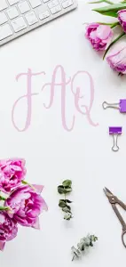 FAQ steht in rosa Buchstaben auf einem Blatt Papier, daneben liegen Blumen