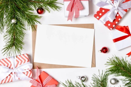 Geschäftliche Weihnachtsgrüße auf weißem Papier, dekoriert mit Weihnachtsgeschenken und Tannenzweigen