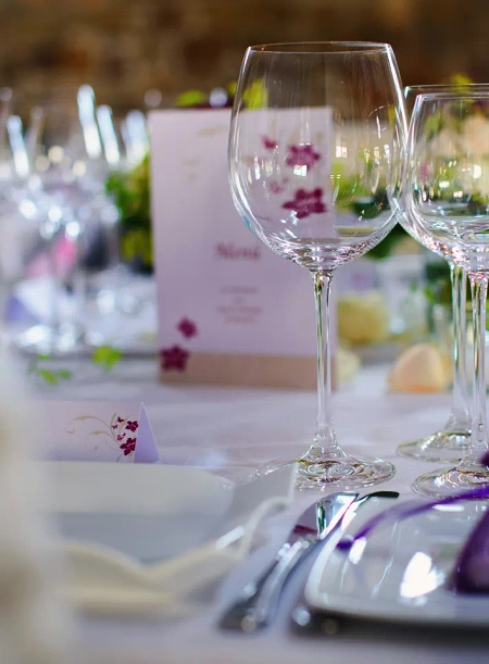 Ein Konfirmationstisch. Im Vordergrund stehen leere Gläser, im Hintergrund sieht man pinke Tischkarten und Einladungskarten, oder Menükarten Konfirmation