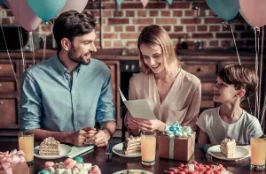 Familie mit Kind feiert Geburtstag rund, Mutter hält Klappkarte, Einladungskarten zum Geburtstag erstellen, Vorlage für Einladung und Einladungen runder Geburtstag, Farben warm und im Vintage Stil gehalten