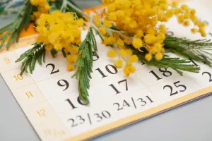 Ein Wandkalender, der auf dem Tisch neben gelben Blumen liegt