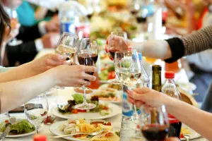 Eine reich gedeckte Tafel, über der 4 Menschen mit gefüllten Weingläsern anstoßen