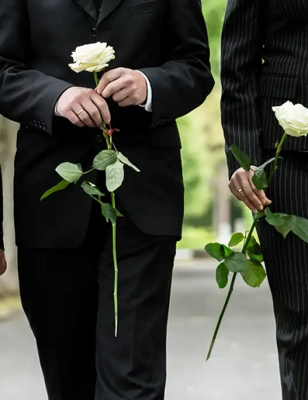 Bestattung, Beerdigung, schwarz gekleidete Menschen mit weißen Rosen in der Hand, Nahaufnahme ohne Gesichter