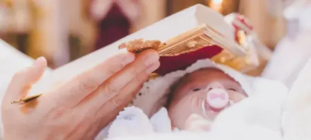 Kind bei Taufe in Kirche, im Arm fest gehalten, Bibel über Kopf des Kindes