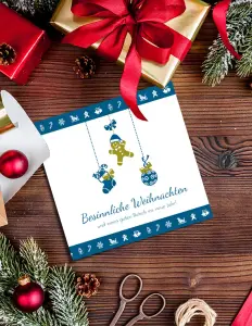 Liebe Weihnachtsgrüße auf Postkarte mit Lebkuchenmann, Holztisch im Hintergrund und Tannenzweige