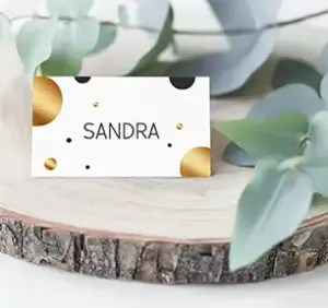 Tischkarte zum Geburtstag oder Hochzeit, beschriftet mit "Sandra" auf weißem Hintergrund mit goldenen und schwarzen runden Kreisen