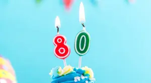 Blauer Cupcake mit Kerze 80 und bunte Streusel, als Vorlage für Einladungskarten Geburtstag