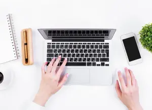Vogelperspektive von einem weißen Schreibtisch mit Laptop darüber das Wort Vorteile