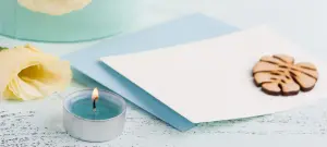 Elegante Einladungskarten zum Geburtstag mit blauem Teelicht und weißer Rose, Umschläge im Hintergrund
