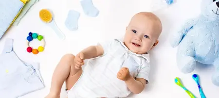 Baby auf Rücken auf Krabbeldecke, Spielzeug im Hintergrund
