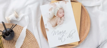 Babykarte mit Text "Maria ist da!" und braunem Papier Umschlag auf Holzteller