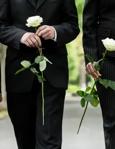 Bestattung, Beerdigung, schwarz gekleidete Menschen mit weißen Rosen in der Hand, Nahaufnahme ohne Gesichter