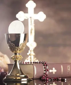 Eine Taufe, eine Konfirmation oder eine Kommunion. Ein Kreuz und ein glänzender Kelch davor