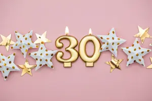 Goldene 30 als Kerzen mit Papierherzen als Deko, Hintergrund rosa, eignet sich als Einladungskarte zum Geburtstag