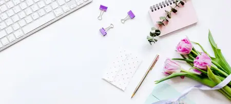 Tisch mit Laptop, Blumen und Umschlag für Einladungskarten zur Hochzeit