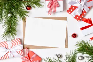 Geschäftliche Weihnachtsgrüße auf weißem Papier, dekoriert mit Weihnachtsgeschenken und Tannenzweigen