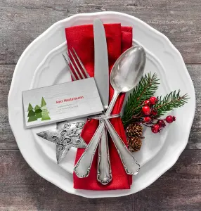 Weihnachtliche Tischkarte auf weißem Teller mit Besteck zur Weihnachtsfeier
