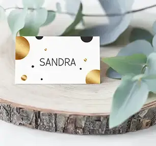Tischkarte zum Geburtstag oder Hochzeit, beschriftet mit "Sandra" auf weißem Hintergrund mit goldenen und schwarzen runden Kreisen
