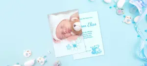 Babykarte als Grußkarte, kleines Baby auf Foto und blaue Elemente als Design, Schnullerkette im Hintergrund