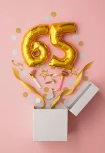 Goldene 65 als Ballon springt aus Geschenkbox, rosa Hintergrund, Motiv für Einladung zum Geburtstag