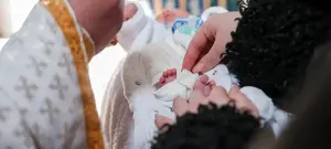 Frau hält Baby im Arm, Taufe des Kindes