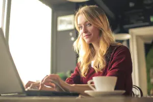 Frau sitzt vor Computer, erstellt Einladungskarten zu runder Geburtstag, Geburtstagseinladungen als Einladungskarten oder Klappkarte im Vintage Stil
