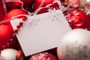 Weiße Weihnachtskarte gestalten, rote Christbaumkugeln im Hintergrund