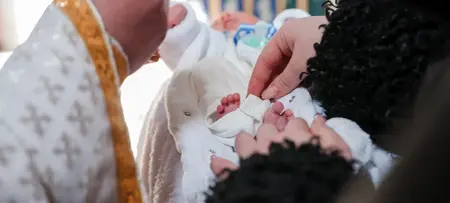 Frau hält Baby im Arm, Taufe des Kindes