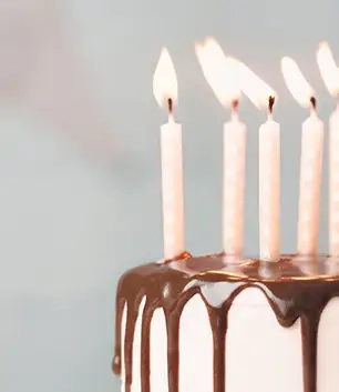 Creme farbene brennende Kerzen auf Kuchen zum runden Geburtstag