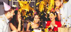 freunde-feiern-geburtstag-mit-partyhueten-und-troeten-goldenes-konfetti-in-der-luft-als-vorlage-fuer-einladung-zum-geburtstag