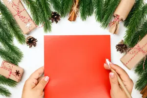 Weihnachtskarten geschäftlich auf rotem Papier, dekoriert mit Weihnachtsgeschenken und Tannenzweigen