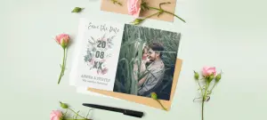 Romantische Hochzeitseinladung mit Datum für den Hochzeitstag sowie Umschlag auf grünem Tisch