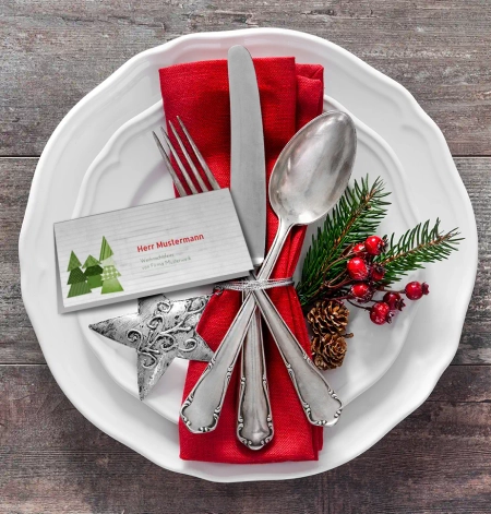 Weihnachtliche Tischkarte auf weißem Teller mit Besteck zur Weihnachtsfeier