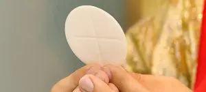 Hostie wird in Händen gehalten, als Symbol für Kommunion Konfirmation