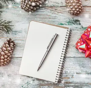 Weißes Notizbuch mit Stift zur Planung der Weihnachtsfeier