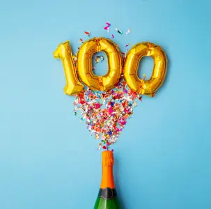 Einladung 100 Geburtstag mit Sektflasche aus der Konfetti schießt