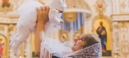 Mutter hält Baby hoch, Taufe in der Kirche