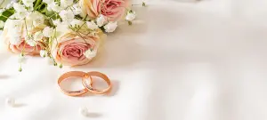 weißer Untergrund mit Hochzeitsringen in Gold und weißen Rosen