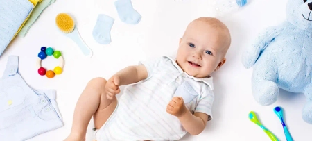 Baby auf Rücken auf Krabbeldecke, Spielzeug im Hintergrund