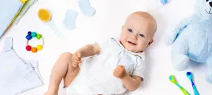 Baby auf Rücken auf Krabbeldecke, Spielzeug im Hintergrund