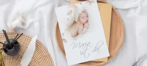 Babykarte mit Text "Maria ist da!" und braunem Papier Umschlag auf Holzteller