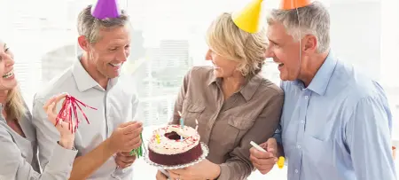 Mann und Frau feiern Geburtstag mit bunten Partyhüten und Kuchen