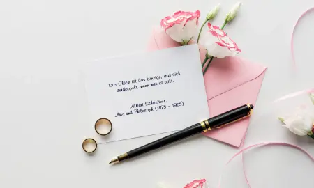 Glückwunschkarte mit geschriebenem Spruch, Füller liegt auf der Karte und zwei Ringe in Gold daneben.