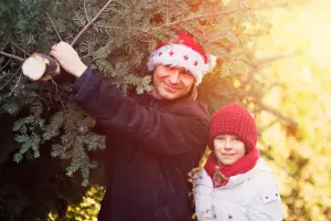Mann und Kind beim Weihnachtsbaum schlagen