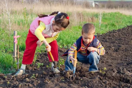 Zwei Kinder graben den Garten um