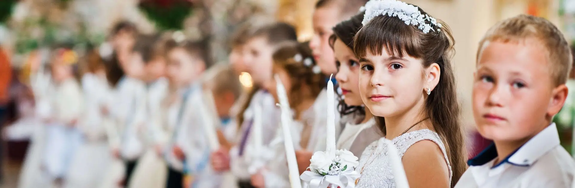 Kommunion: Kinder stehen in der Kirche. Mädchen blickt in die Kamera.